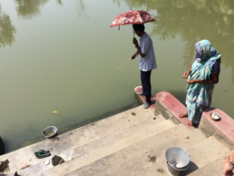Man fishing and a woman standing besides watching